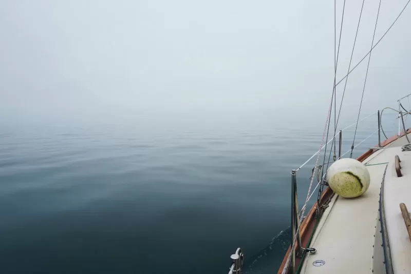 white sailboat on ocean with fog